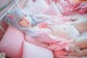 A woman laying on a bed with pink pillows and stuffed animals.
