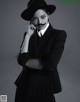 A woman in a black suit and hat with a fake mustache.