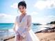 A woman in a white dress standing on a beach.