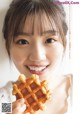 A woman holding a waffle in front of her face.