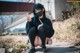 A woman wearing a face mask sitting on the ground.