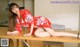 A woman in a red kimono sitting on a wooden table.