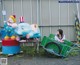 A woman sitting in a cart next to a clown and an elephant.