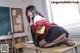 A woman in a school uniform sitting on a desk.