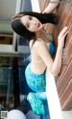 A woman in a blue and white bikini leaning against a wall.