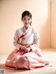 A woman in a pink and white hanbok sitting on the floor.