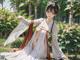 A woman in a white kimono sitting in the grass.